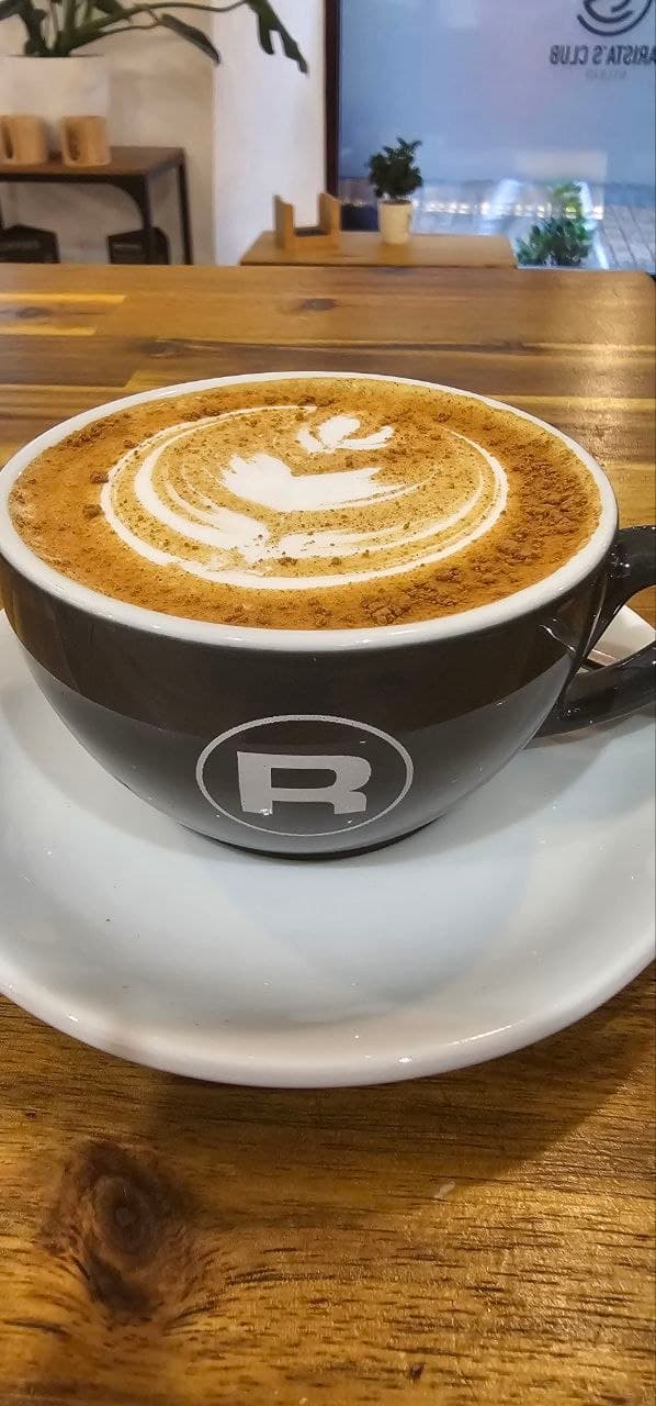 Cappuccino de Baristas Club con latte art servido sobre una mesa de madera